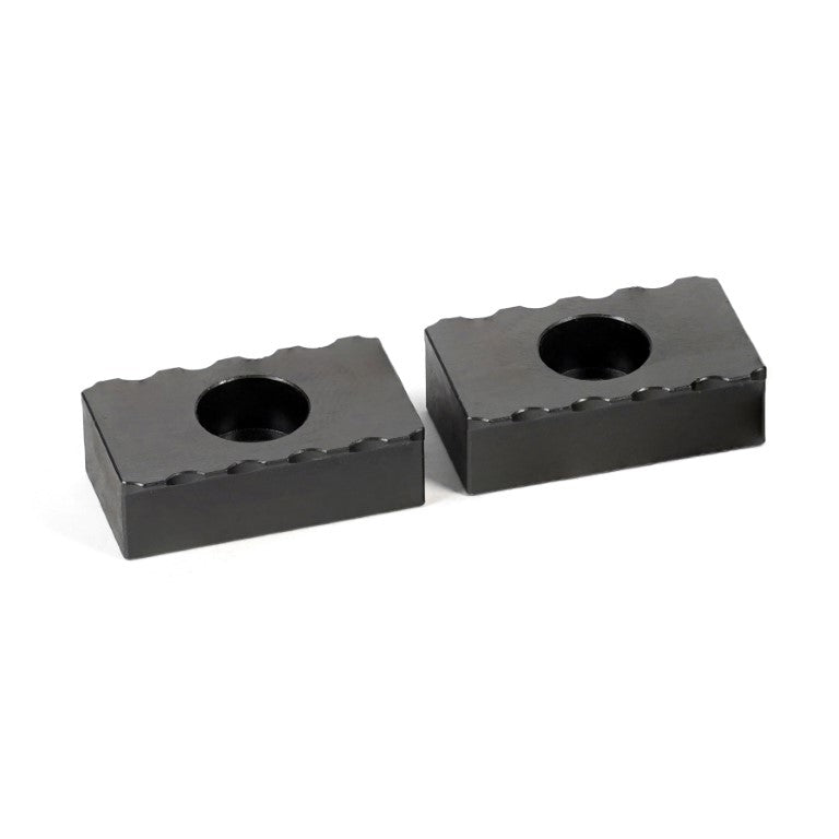 Two black serrated grippers with a central hole, designed for tooling and workholding in manufacturing.